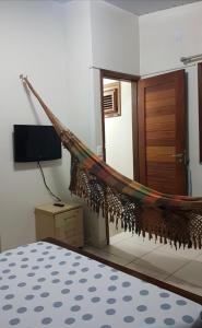 a hammock in a room with a tv and a bed at Casa de praia Luiz Correia paraíso azul in Luis Correia