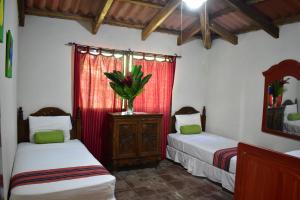 a bedroom with two beds and a vase on a dresser at Thermal Paradise Villa in Caluco