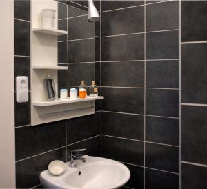 ブダペストにあるCentral Apartmentの黒いタイル張りの壁、洗面台付きのバスルーム