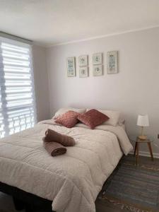 um quarto com uma cama grande com almofadas em Departamento céntrico en Puerto Varas em Puerto Varas