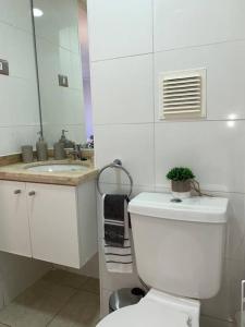 a white bathroom with a toilet and a sink at Departamento céntrico en Puerto Varas in Puerto Varas