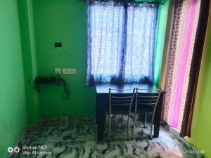 a green room with two chairs and a window at Radha Rani lodge in Siliguri