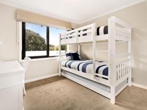 a white bedroom with bunk beds and a window at Sandy Feet Retreat in Cape Woolamai