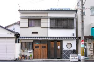 een wit huis met houten deuren en ramen bij Central in Osaka