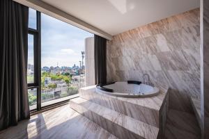 ein Badezimmer mit Badewanne und großem Fenster in der Unterkunft Ayathorn Bangkok in Bangkok