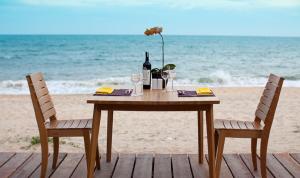 a table with a bottle of wine and glasses on the beach at Villa Aria Boutique Muine in Mui Ne