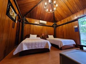 a bedroom with two beds and a chandelier at CASA ECO Mekong Resort in Can Tho