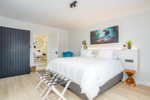 a bedroom with a large white bed and a chair at Droom Guesthouse in Franschhoek