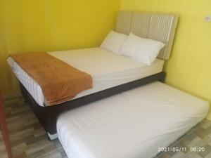 two twin beds in a room with yellow walls at Pondok Wammy Syariah in Cigasong