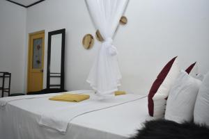 a bedroom with a bed with white sheets and a mirror at Sigiri Rock Side Home Stay in Sigiriya