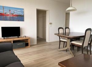 uma sala de estar com uma mesa de jantar e uma televisão em Haus Atlantic Whg. 601 em Cuxhaven