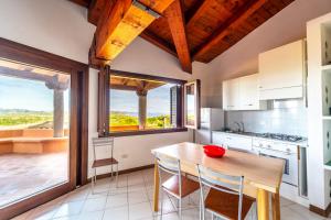 una cucina con tavolo e sedie e una grande finestra di ISS Travel, Panoramic Coda Cavallo Cottages - 10 km from San Teodoro a San Teodoro