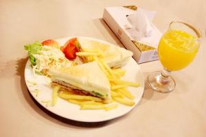a plate with a sandwich and french fries and a glass of orange juice at Shalimar Tower Hotel Lahore in Lahore