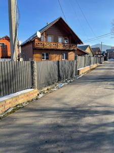 a wooden house with a fence next to a road at Орел in Mykulychyn