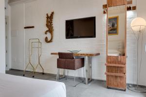 1 dormitorio con escritorio y TV en la pared en Casa Gardenia -affittacamere, en Gatteo