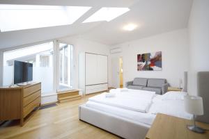 a white bedroom with a bed and a television at HeyMi Apartments Oper in Vienna