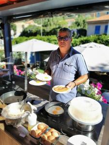 a man is sitting at a table with plates of food at Hotel L'Escapade in Le Lavandou