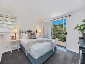 a white bedroom with a bed and a window at Sweet Cottage, sleeps 4 - stroll to Maleny in Maleny
