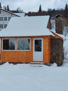eine Holzhütte mit einem schneebedeckten Dach in der Unterkunft Апартаменти "Захід сонця " in Slawske