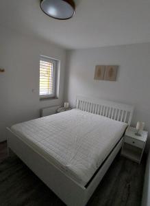 a white bedroom with a bed and a window at Apartmán08 in Dolní Morava