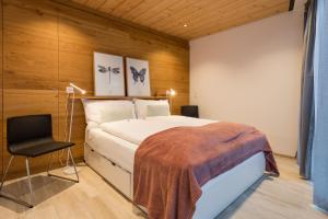 1 dormitorio con 1 cama y 1 silla en Montela Hotel & Resort - Montela Pavillon, en Saas-Grund