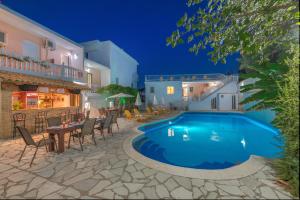 a swimming pool with chairs and a table next to a building at Panorama in Laganas