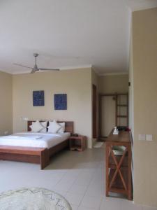 Schlafzimmer mit einem Bett und einem Holztisch in der Unterkunft Coral House near Villa Bluu in Jambiani