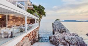 a restaurant on the water next to a cliff at Blanche Cliff Apartments in Sveti Stefan