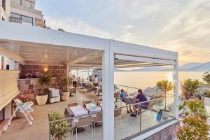 a balcony with people sitting at tables on a building at Blanche Cliff Apartments in Sveti Stefan