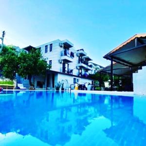 een groot zwembad met blauw water voor een gebouw bij TUTHALİYA HOTEL in Gelemiş