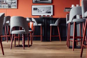 a bar with gray chairs and an orange wall at Dormy House in Étretat