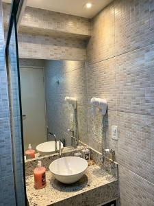 a bathroom with two sinks and a mirror at Tabatinga Residence Flat Pé na Areia II in Conde