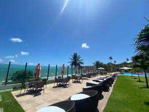 a row of tables and chairs with the ocean in the background at Tabatinga Residence Flat Pé na Areia II in Conde