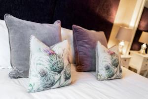a group of pillows on a bed with at The Pines - Luxury 3-Bed Apartment Near Golf & Spa, Gleneagles, Auchterarder in Auchterarder