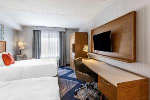 a hotel room with two beds and a desk with a tv at Comfort Inn in Sarnia