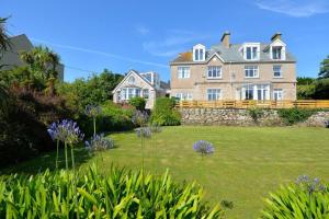 a large house with a yard with purple flowers at Rosemorran Holiday Apartments in St Ives