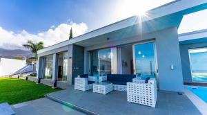 un patio con un sofá azul y sillas frente a una casa en Luxury Villa Lázaro Elegancia y Exclusividad en Santa Úrsula