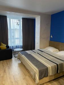 a bedroom with a large bed and a blue wall at Magic Days Apartments in Chernihiv