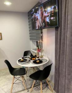 een tafel met stoelen en een tv aan de muur bij Crystal Twin Apartment in Gulbene