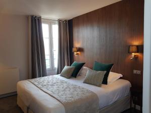 a hotel room with a large bed with green pillows at Dormy House in Étretat