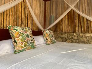 uma cama com duas almofadas em cima em Piña Coloradas Ecolodge em Yuluc