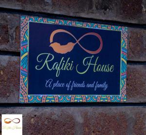 a sign hanging on a brick wall with a pair ofbons at Rafiki House Nanyuki in Nanyuki