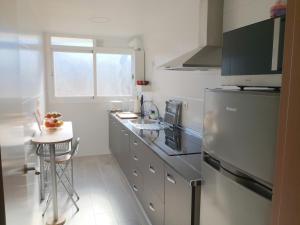 eine Küche mit einem Kühlschrank aus Edelstahl und einem Tisch in der Unterkunft confortable y luminoso piso 5 camas, parking gratis in Málaga