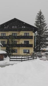 ein schneebedecktes Gebäude mit einem Parkplatz davor in der Unterkunft Apartment House Seerose in Obertraun