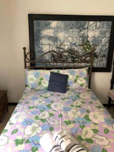 a bed with a floral comforter with a blue pillow at Hostel Limão Doce in Nova Friburgo