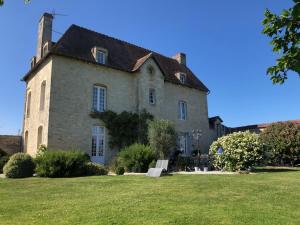 uma grande casa de pedra com um jardim de relva em Domaine "Les Bois Flottes" dans Maison de Charme au bord de mer et proche de Cabourg em Merville-Franceville-Plage