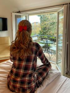 ヴィルパザルにあるVida`s houseの窓を見ながらベッドに腰掛けている女性