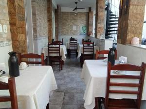 a restaurant with tables and chairs with white tablecloths at Pousada Taquinha Paraty in Paraty