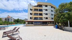 a building with chairs and a pool in front of it at Merit Plaza Standard - Beira Mar in Florianópolis