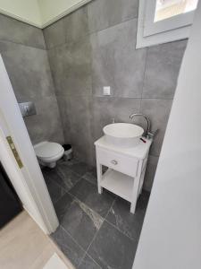 La salle de bains est pourvue d'un lavabo blanc et de toilettes. dans l'établissement Lefkada Triola Apartments, à Leucade